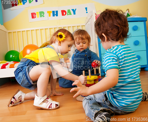 Image of Two boys and girl playing with toy pyramid puzzle