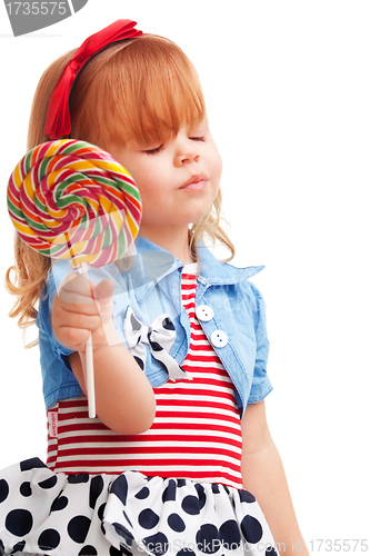 Image of Happy girl smiling and holding lollipop, with closed eyes