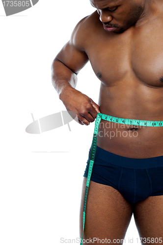 Image of Muscular man measuring his waist