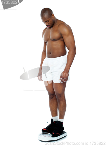 Image of Athlete measuring his weight on weighing machine