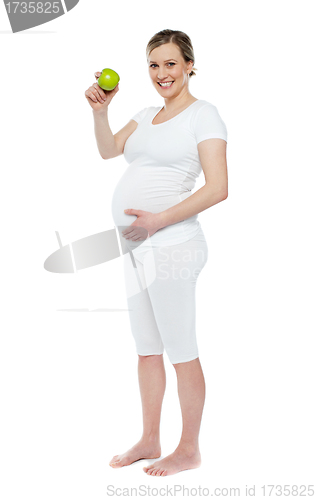 Image of Pregnant woman showing fresh green apple