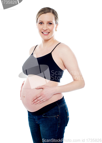 Image of Smiling pregnant woman caressing her belly