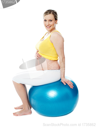 Image of Relaxed pregnant woman sitting on pilate ball
