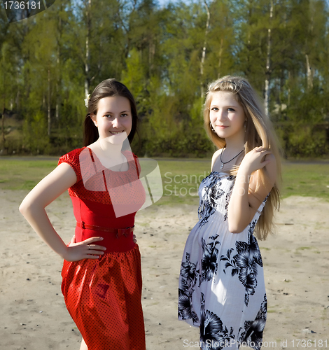 Image of Two girls in dresses walk in the park