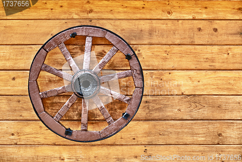 Image of Old wagon wheel on a wooden wall