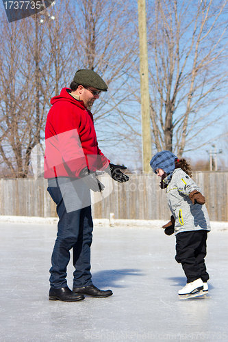 Image of Father teaching daughter how to ice skate