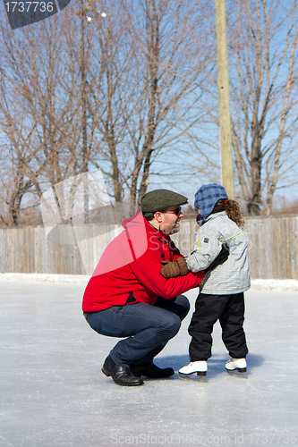 Image of Father teaching daughter how to ice skate