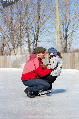 Image of Father teaching daughter how to ice skate