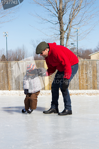 Image of Father teaching son how to ice skate