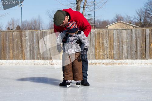 Image of Father teaching son how to ice skate