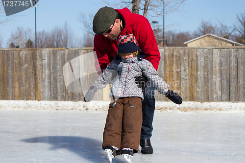 Image of Father teaching son how to ice skate