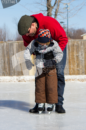 Image of Father teaching son how to ice skate