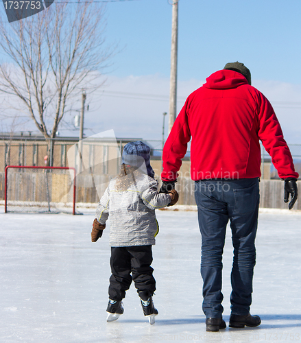 Image of Father teaching daughter how to ice skate