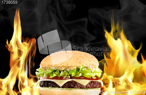 Image of Hamburger with fire on black background