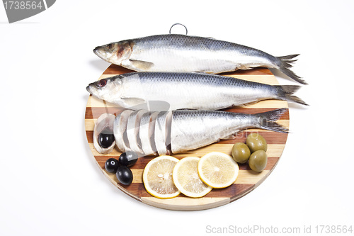 Image of Fish with lemon and olive on wooden plate