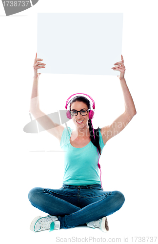 Image of Casual musical woman holding blank billboard