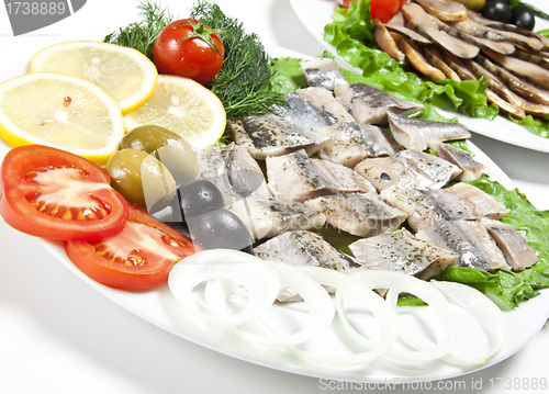 Image of fish slices served with tomato and olives