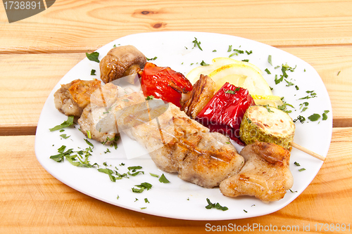 Image of grilled meat pieces on wood sticks with vegetables