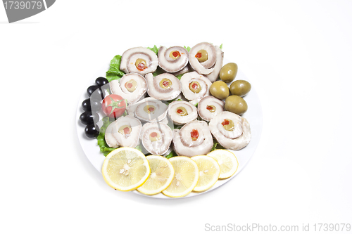 Image of fish slices served with tomato and olives, and lemon