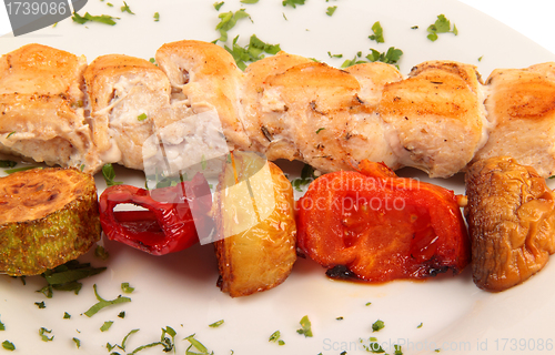 Image of grilled meat pieces on wood sticks with vegetables close up