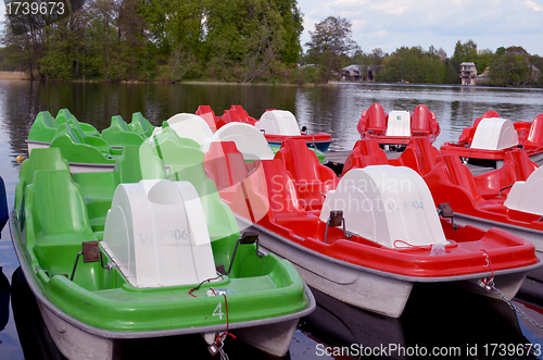 Image of Water bicycles green and red locked at lake pier 