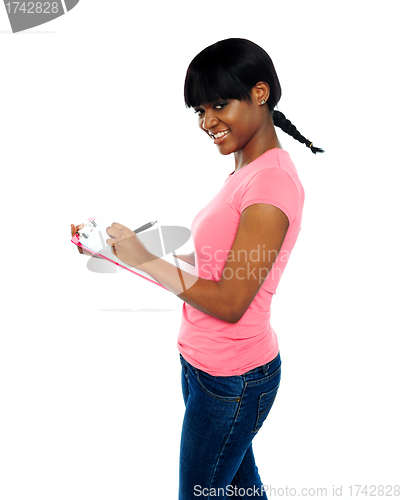 Image of Smiling girl writing on clipboard