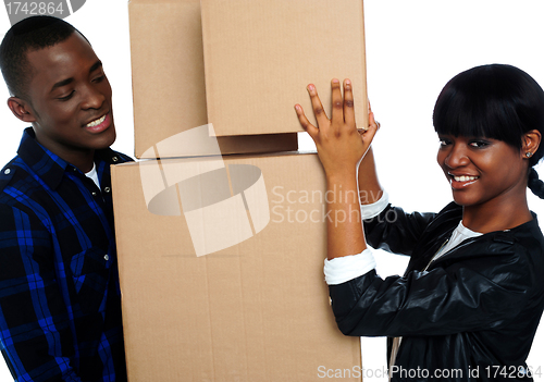 Image of Young couple holding and moving boxes