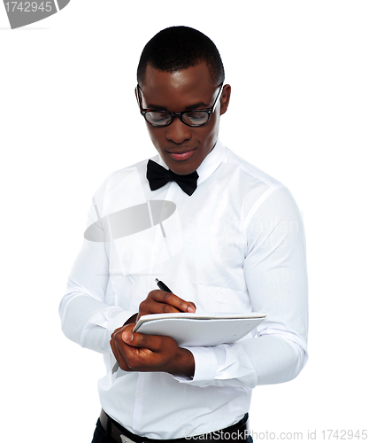 Image of Confident young man writing on notepad