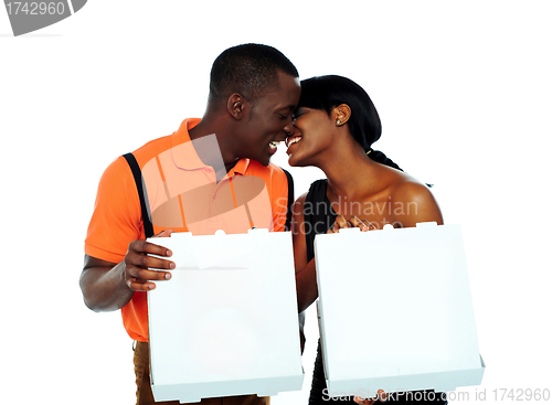 Image of Black couple kissing and holding pizza boxes