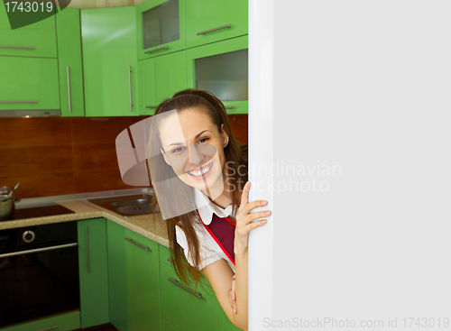 Image of Young woman on kitchen near refrigerator