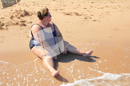 Image of overweight woman sitting on beach