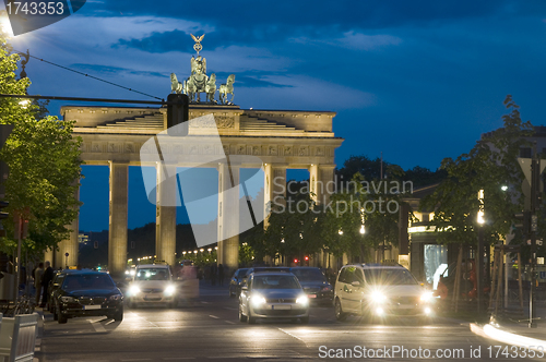 Image of  Brandenburg Gate lit with car pedestrian traffic at night on Un