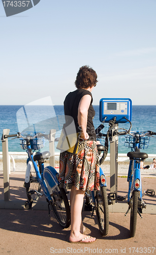 Image of tourist looking at bicycle rental machine Nice France