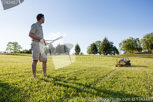 Image of Senior man cutting grass with shears