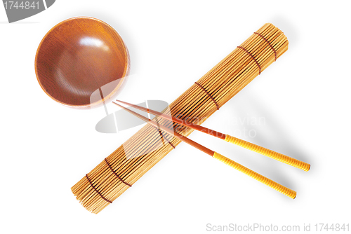 Image of rolled bamboo mat with a pair of chopsticks  and wooden bowl 