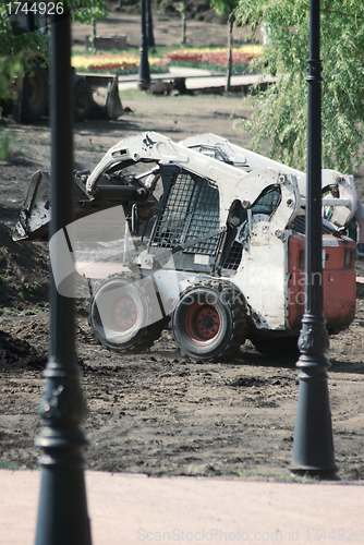 Image of mini wheel excavator working in city park at the spring