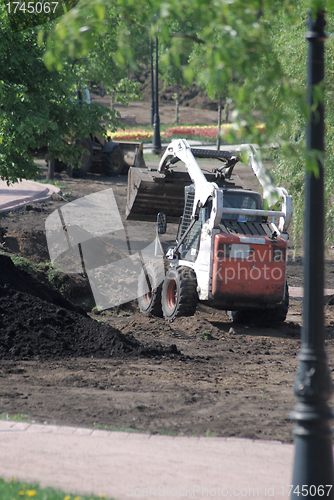 Image of mini wheel excavator working in city park at the spring