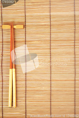 Image of Chopsticks on brown bamboo matting background 