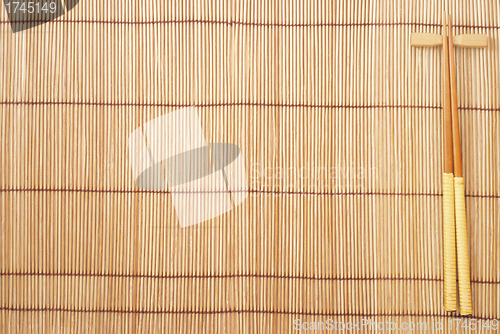 Image of Chopsticks on brown bamboo matting background 