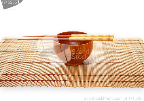 Image of Chopsticks with wooden bowl on bamboo matting background 