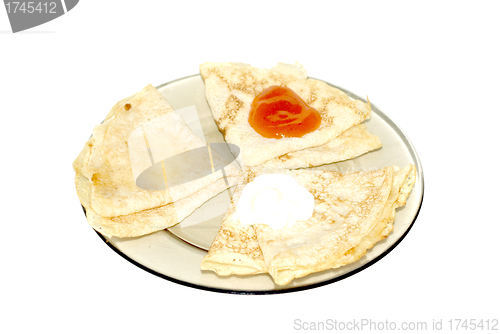 Image of three pancakes  with jam, sour cream and honey 