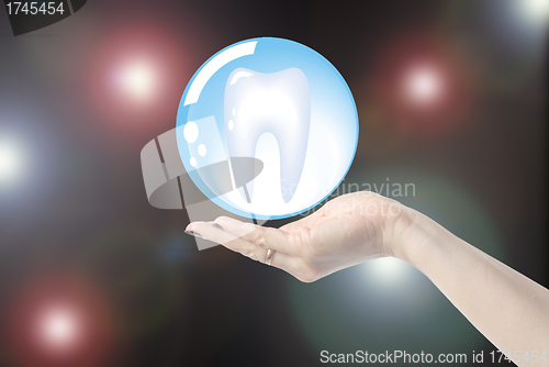 Image of hands holding tooth in glass sphere, dentistry  