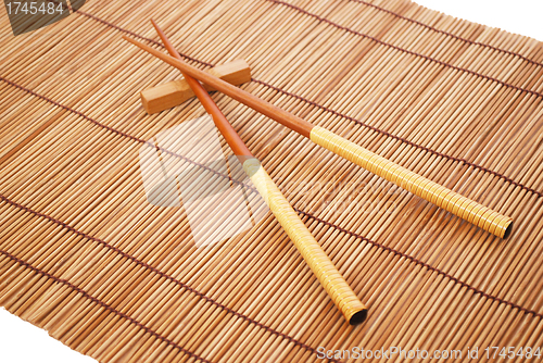 Image of Chopsticks on brown bamboo matting background 