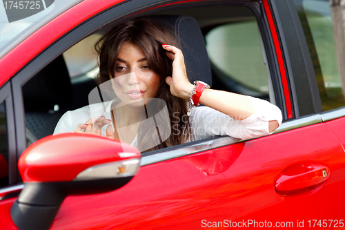 Image of Young pretty woman in the red car