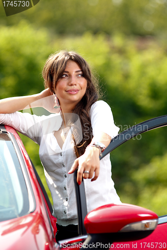 Image of Young pretty woman in the red car