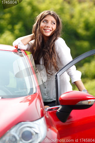 Image of Young pretty woman in the red car