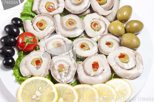 Image of fish slices served with tomato and olives