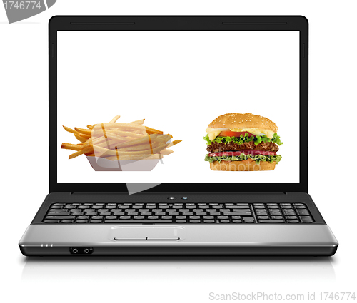 Image of Laptop computer close-up with an hamburger and french fries