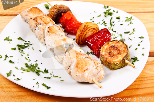 Image of grilled meat pieces on wood sticks with vegetables