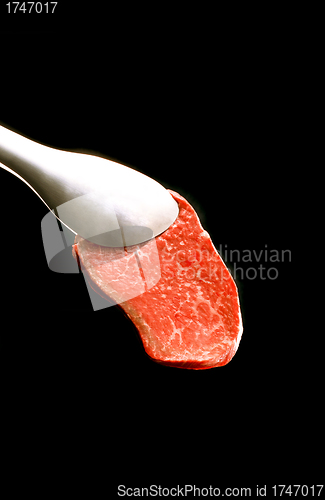 Image of piece of meat on a fork isolated on black